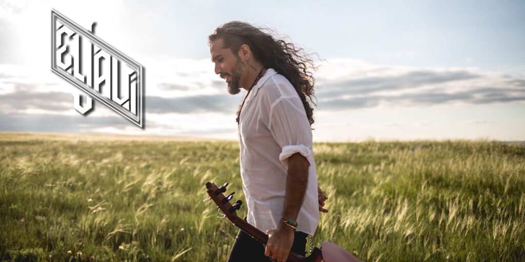 El Javi holds a guitar in a field