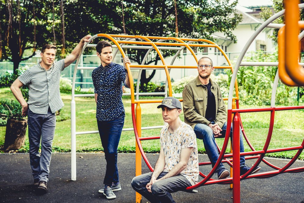 The four members of Kneebody pose on a playground's jungle gym